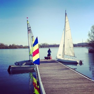 Vier Boote liegen am Steg, zwei große Segelboote, ein kleines Segelboot und ein kleines Motorboot.