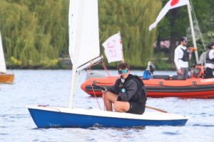 Torge auf dem ILCA bei Jugendsegeltreffen, im Hintergrund ein Boot der Wettfahrtleitung